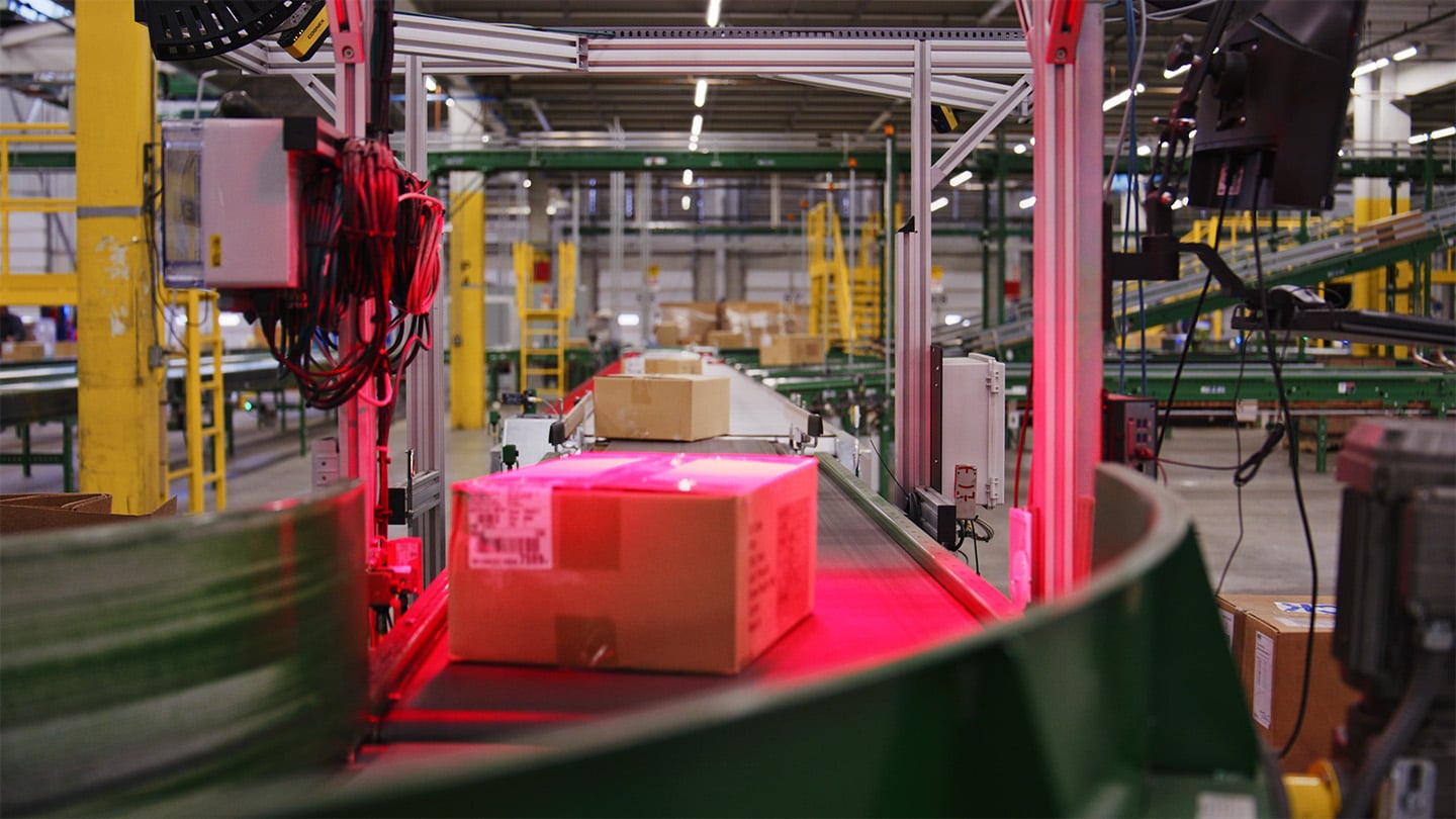 A box on a conveyor belt passes under a scanner.